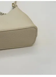 Close-up of the widened base and litchi grain texture on the beige leather handbag