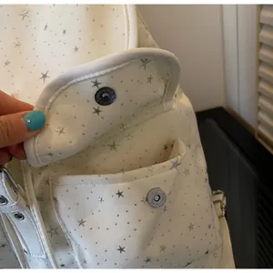 Detail of the strong magnetic buckle on a white canvas backpack with star print pattern