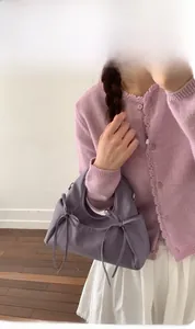 Dettaglio della borsa a mano plissettata in pelle viola con fiocchi decorativi laterali