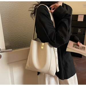 Détail d'un sac seau en cuir grainé crème avec fermoir doré et bandoulière large