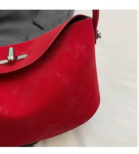 Close-up of red leather handbag showing silver metal twist lock and smooth matte texture