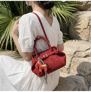Detail der roten Wildleder Kelly Handtasche mit Pferdeanhänger im Sonnenlicht