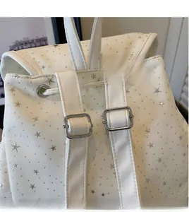 Detail of adjustable white canvas backpack straps with silver star pattern and metal buckle