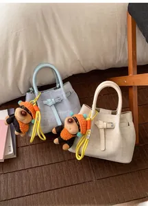 Detail of woven bucket bags in blue and beige with cute plush dog pendants