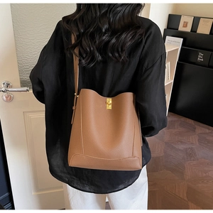 Sac seau en cuir marron avec fermoir doré sur modèle pour un style de transport quotidien