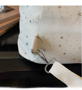 Detail of high-gloss silver metal hardware and star print on cream canvas backpack