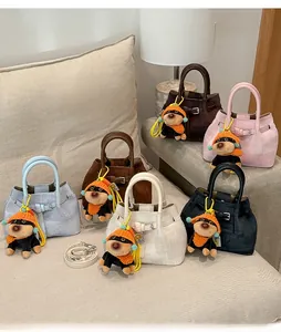 Detailed view of tweed bucket bags in multiple colors with adorable dog charms and leather trim