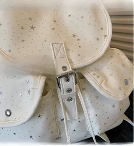 Close-up of beige canvas backpack featuring silver star studs and metallic buckles