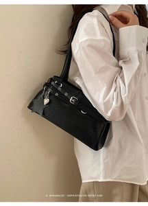 Sac à bandoulière chic en similicuir noir avec breloques porté par le mannequin