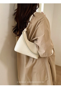 Detailed view of white lychee leather handbag with chunky metal chain and fine strap