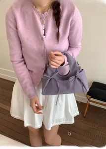 Dettaglio della borsa lilla con fiocchi indossata da una modella in cardigan viola