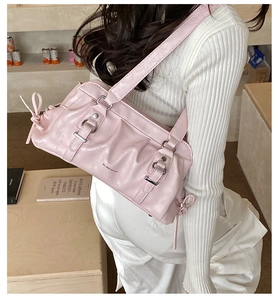 Detail of light pink pleated leather shoulder bag with bow accents on white outfit