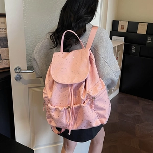 Detail of pink backpack with silver star patterns showing the side pocket and drawstring closure