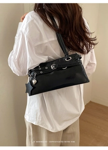 Détail du sac bandoulière en cuir noir avec breloques étoiles et boucle argentée