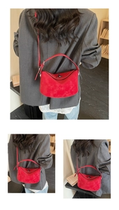 Detail of red suede half-moon handbag with metallic twist lock and adjustable strap