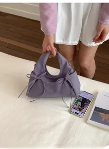 Dettaglio della borsa a mano lavanda con fiocchi e trama elegante in pelle opaca