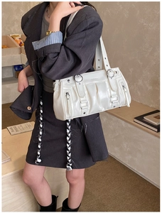 Detailansicht der weißen, glänzenden Plissee-Tasche mit Metallösen und Schulterriemen