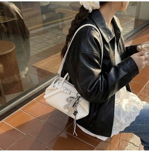 Schicke weiße Lederhandtasche mit Elefanten-Anhänger in einem urbanen Streetstyle-Ambiente