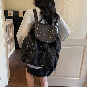 Close-up of black drawstring backpack with white star pattern and functional side pockets