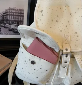 Detail of white star-studded backpack featuring a front pocket and durable hardware