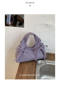 Dettaglio borsa a pieghe color lavanda con fiocchi decorativi e trama in ecopelle