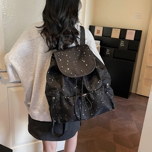 Detail view of the star pattern drawstring backpack with flip cover on model's back