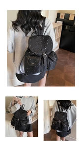 Detail of black canvas backpack with white star patterns featuring buckle straps and side pockets