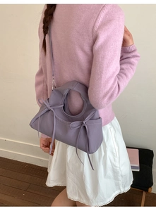 Dettaglio della borsa a mano plissettata viola chiaro con fiocco e tracolla vista sul modello