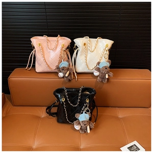 Close-up of quilted bucket bags with gold chain straps and cute bear charms