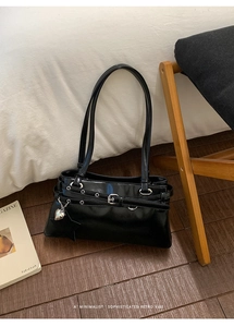 Détail d'un sac à main en cuir verni noir avec boucle et breloques cœur et étoile