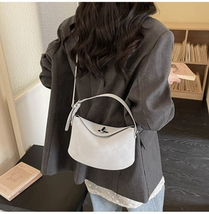 Detail view of light grey matte faux leather handbag with silver rotary buckle on a model
