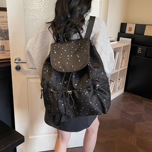 Detail shot of black drawstring backpack with silver star patterns and side zipper pockets