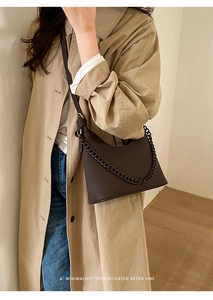 Detail of dark brown lychee leather handbag with a chain strap and geometric cut design