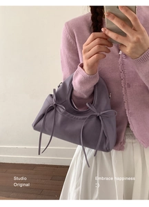 Dettaglio della borsa viola con fiocco indossata da una modella con outfit casual