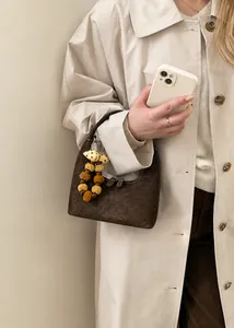 Detail der braunen Retro-Hobo-Handtasche mit Punkt-Schleife und Plüschball-Anhänger