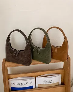 Drei Hobo-Taschen aus Wildleder in Dunkelbraun, Olivgrün und Karamell auf Holzständer