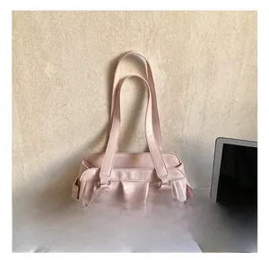 Close-up of pink leather handbag with elegant pleats, metal rings and dual handles