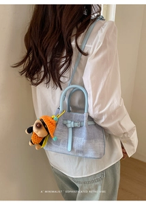 Detail of light blue textured tote bag featuring a cute plush dog charm and strap design