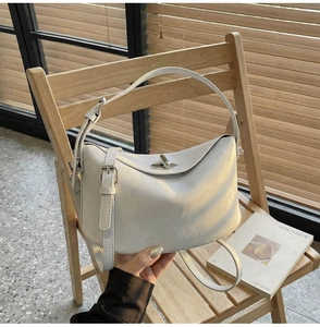 Close-up of the beige leather bucket bag with metal turn-lock and adjustable strap