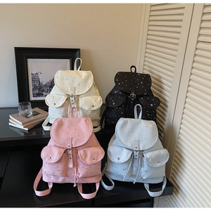 Detail showing four colors of star pattern canvas backpacks with metal buckle pockets
