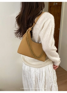 Close-up of pebble leather texture and gold chain detail on camel shoulder bag
