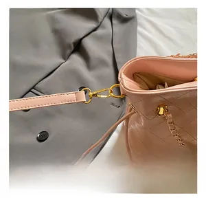 Close-up of golden metal hooks and pink leather strap on quilted shoulder bag