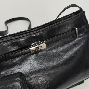 Detailansicht aus nächster Nähe von schwarzem Leder und silbernem Drehverschluss der Tasche