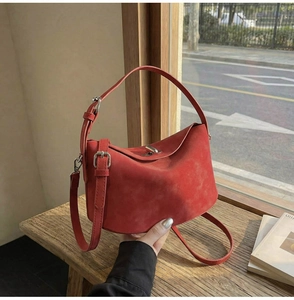 Detail of red suede bucket bag with matte texture and elegant silver hardware finish