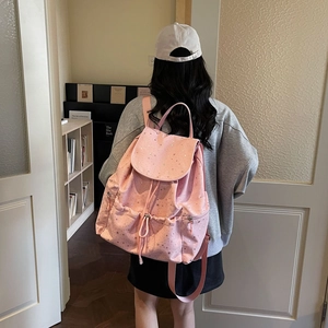 Pink drawstring backpack with silver star patterns showing flap and buckle pocket details