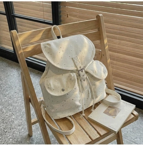 Detail of canvas backpack with star patterns on a wooden chair in soft lighting
