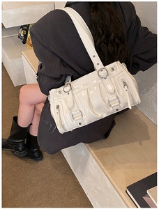 Nahaufnahme der plissierten cremefarbenen Lackleder-Tasche mit Metallreißverschlüssen