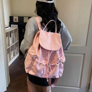 Detailed view of a pink drawstring backpack with silver star patterns on a person