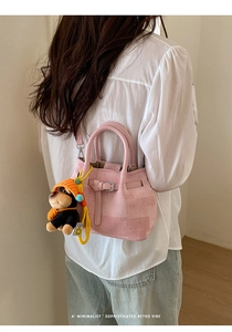 Pink minimalist handbag with cute black dog plush charm and buckled strap detail