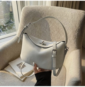Detail view of a light gray leather bucket bag featuring a silver twist lock and slim strap